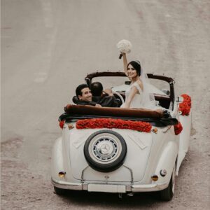 A newlywed couple celebrates their wedding in a vintage convertible adorned with roses, driving into a new future.
