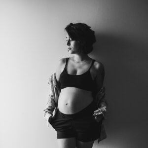 A serene black and white portrait of a pregnant woman looking away, showcasing tranquility and grace.
